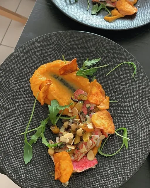 Assiette dressée avec purée orangée, amandes et jeunes pousses